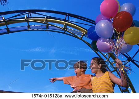 Low angle view of a brother and sister in an amusement park View Large Photo Image Stock Image - Low angle view of a brother and sister in an amusement park. Fotosearch