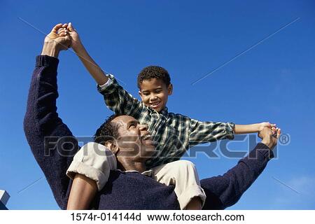 Low angle view of a father carrying his son on his shoulders View Large Photo Image Stock Image - Low angle view of a father carrying his son on his shoulders. Fotosearch