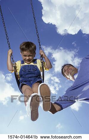 Low angle view of a father pushing his son on a swing View Large Photo Image Stock Image - Low angle view of a father pushing his son on a swing. Fotosearch
