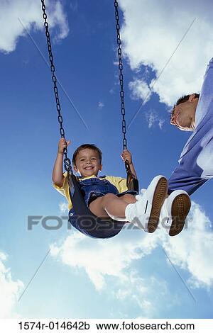 Low angle view of a father pushing his son on a swing View Large Photo Image Stock Image - Low angle view of a father pushing his son on a swing. Fotosearch
