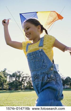 Low angle view of a girl flying a kite View Large Photo Image Stock Image - Low angle view of a girl flying a kite. Fotosearch