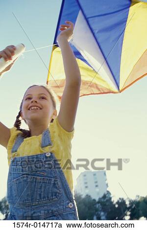Low angle view of a girl flying a kite View Large Photo Image Stock Image - Low angle view of a girl flying a kite. Fotosearch