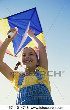 Low angle view of a girl flying a kite View Large Photo Image Stock Photo - Low angle view of a girl flying a kite. Fotosearch
