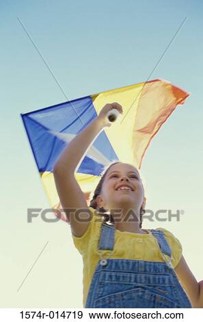 Stock Photo - Low angle view of a girl flying a kite. Fotosearch