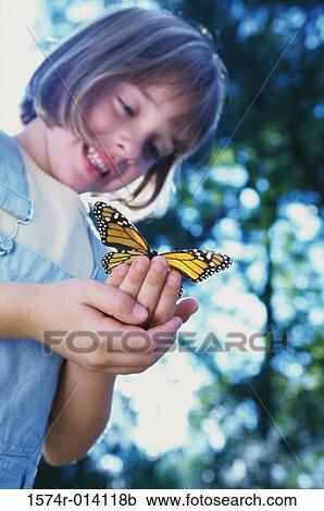 Low angle view of a girl holding a butterfly View Large Photo Image Stock Image - Low angle view of a girl holding a butterfly. Fotosearch