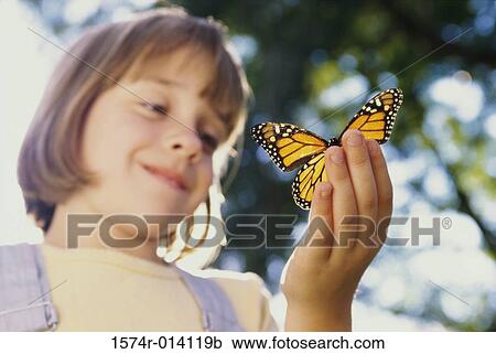 Stock Image - Low angle view of a girl holding a butterfly. Fotosearch