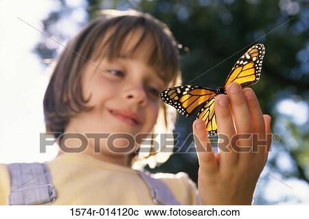 Stock Image - Low angle view of a girl holding a butterfly. Fotosearch