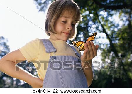 Stock Image - Low angle view of a girl holding a butterfly. Fotosearch