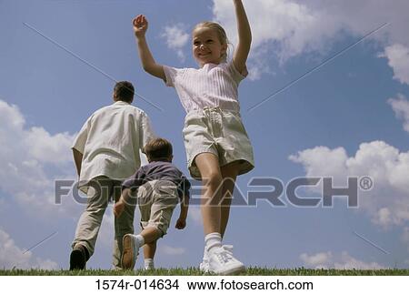 Picture - Low angle view of a girl standing with her arms raised. Fotosearch