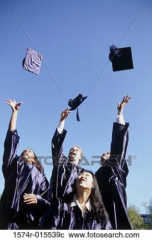Stock Image - Low angle view of a group of young graduates throwing their graduation caps in the air. Fotosearch