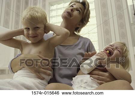 Stock Photograph - Low angle view of a mother holding her son and daughter. Fotosearch