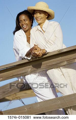 Stock Image - Low angle view of a mother standing with her daughter on a deck. Fotosearch
