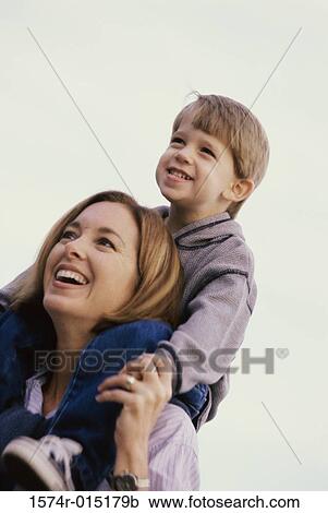 Low angle view of a son sitting on his mother's shoulders View Large Photo Image Stock Image - Low angle view of a son sitting on his mother's shoulders. Fotosearch