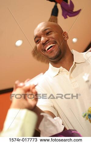 Stock Image - Low angle view of a young man handing a credit card to a person. Fotosearch
