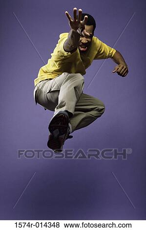 Low angle view of a young man jumping View Large Photo Image Stock Photo - Low angle view of a young man jumping. Fotosearch