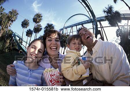 Stock Image - Low angle view of parents with their son and daughter smiling in an amusement park. Fotosearch