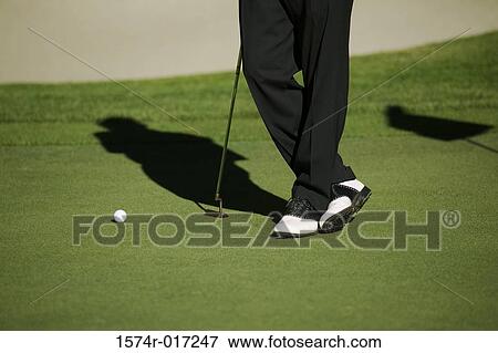 Stock Photo - Low section view of a person standing with a golf club. Fotosearch