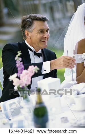 Stock Image - Mature man toasting with champagne at a wedding reception. Fotosearch