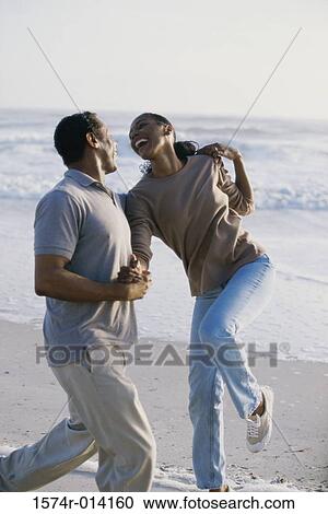 Stock Image - Mid adult man flirting with a mid adult woman on the beach. Fotosearch