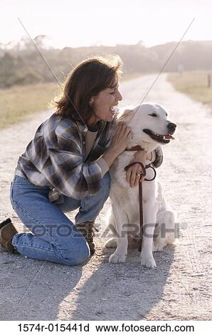 Stock Image - Mid adult woman hugging her dog. Fotosearch