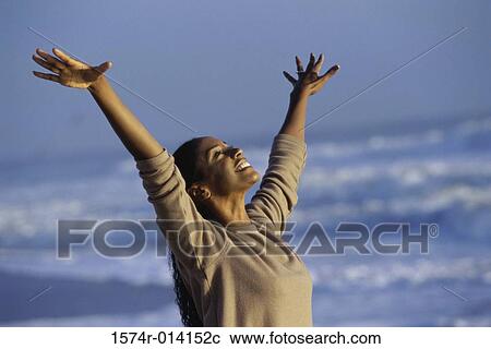 Stock Image - Mid adult woman stretching on the beach. Fotosearch