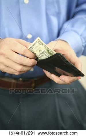 Stock Image - Mid section view of a mid adult man holding a wallet. Fotosearch