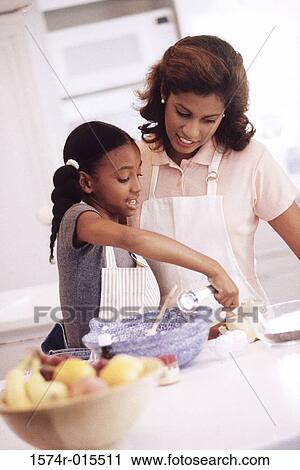 Stock Image - Mother and daughter preparing food in the kitchen. Fotosearch