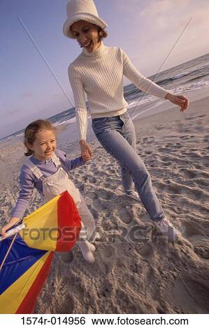 Mother and daughter walking on the beach View Large Photo Image Stock Photograph - Mother and daughter walking on the beach. Fotosearch