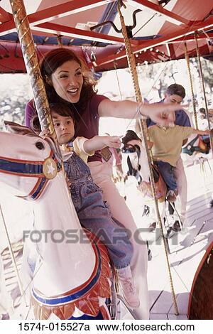 Stock Image - Mother and son sitting on a carousel in an amusement park. Fotosearch
