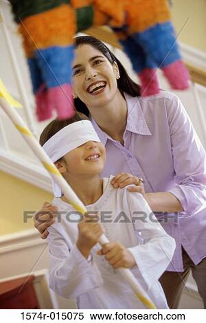 Mother helping her daughter hit a pinata View Large Photo Image Stock Photography - Mother helping her daughter hit a pinata. Fotosearch