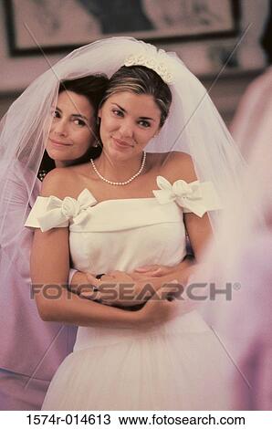 Stock Image - Mother hugging her newlywed daughter from behind. Fotosearch
