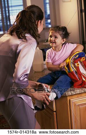 Stock Image - Mother putting a shoe on her daughter's foot. Fotosearch