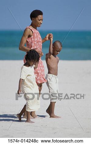 Mother with her two children walking on the beach View Large Photo Image Stock Image - Mother with her two children walking on the beach. Fotosearch