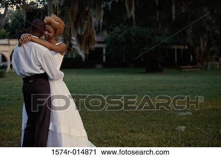 Newlywed couple embracing each other in a park View Large Photo Image Stock Image - Newlywed couple embracing each other in a park. Fotosearch
