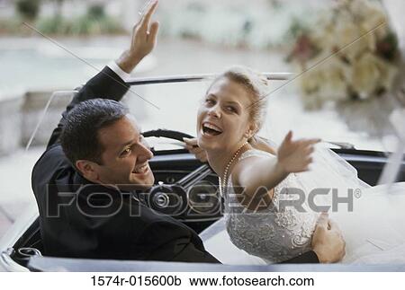 Stock Image - Newlywed couple sitting in a convertible car. Fotosearch