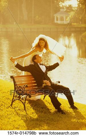 Stock Image - Newlywed couple sitting on a park bench. Fotosearch