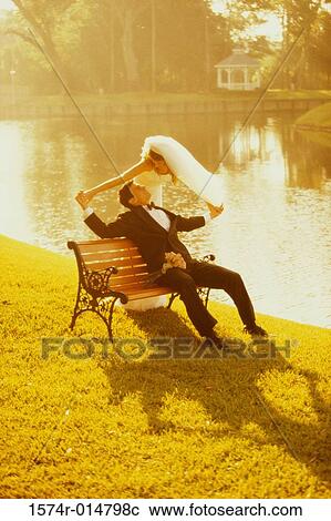 Newlywed couple sitting on a park bench View Large Photo Image Stock Image - Newlywed couple sitting on a park bench. Fotosearch