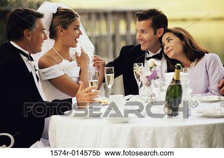 Stock Image - Newlywed couple sitting with wedding guests. Fotosearch