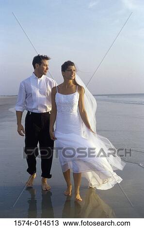 Stock Image - Newlywed couple walking on the beach. Fotosearch