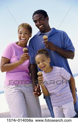 Stock Image - Parents and their daughter holding ice cream cones and smiling. Fotosearch