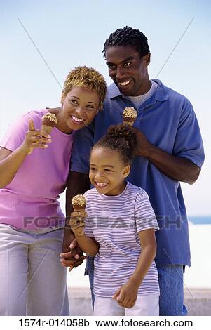 Stock Image - Parents and their daughter holding ice cream cones and smiling. Fotosearch