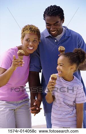 Stock Image - Parents and their daughter holding ice cream cones and smiling. Fotosearch