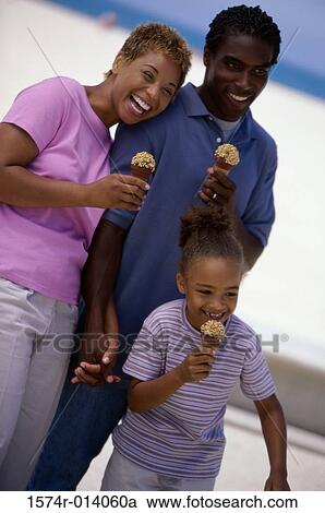Stock Image - Parents and their daughter holding ice cream cones and smiling. Fotosearch