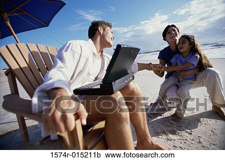 Stock Image - Parents and their daughter playing on the beach. Fotosearch