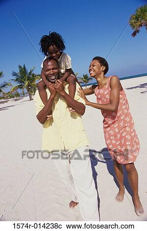 Stock Image - Parents and their daughter walking on the beach. Fotosearch