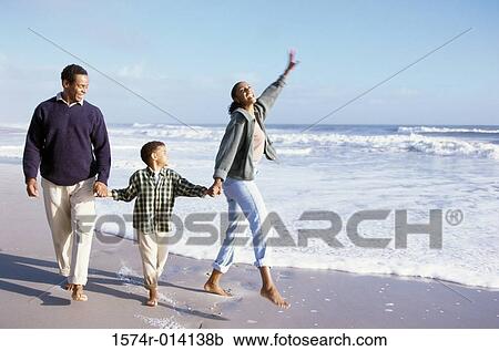 Stock Image - Parents and their son walking on the beach. Fotosearch