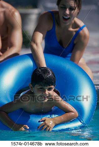 Stock Image - Parents and their two children playing in a swimming pool. Fotosearch