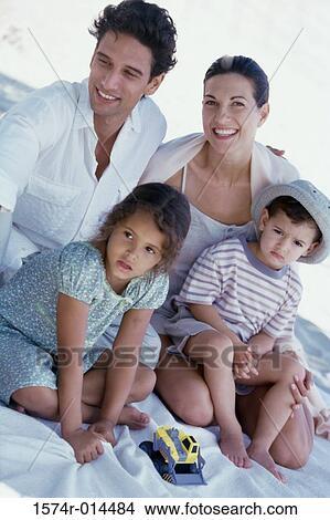 Parents and their two children sitting on the beach View Large Photo Image Picture - Parents and their two children sitting on the beach. Fotosearch