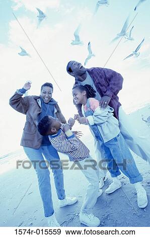 Parents and their two children standing on the beach View Large Photo Image Stock Photo - Parents and their two children standing on the beach. Fotosearch