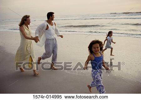 Stock Photography - Parents and their two daughters running on the beach. Fotosearch
